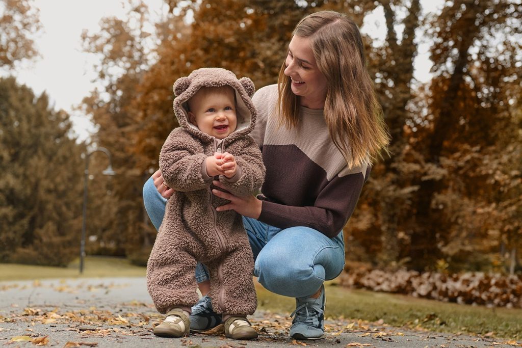 Mama z otrokom, oblečenim v kombinezon-medvedek